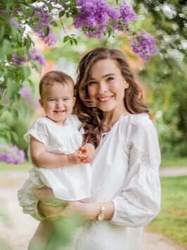 Beautiful young mother and daughter near the blossoming lilac