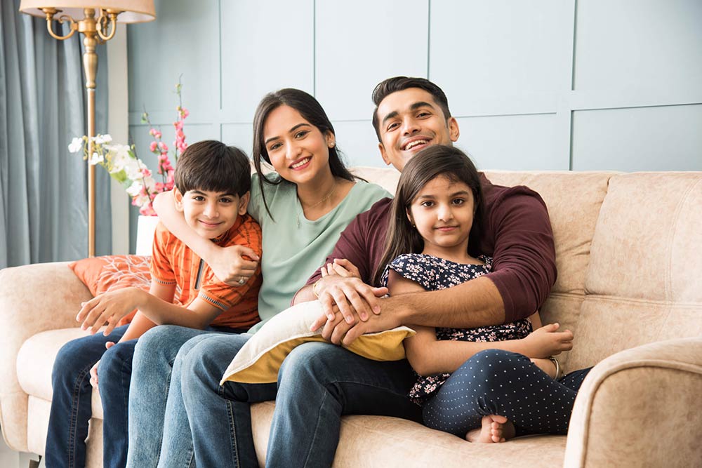 Happy Indian Asian young family while sitting on sofa.